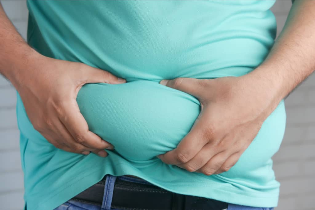 A man holding his belly fat through his t-shirt.