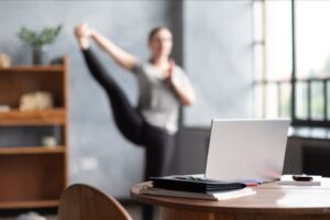 Woman stretching in front of a laptop.